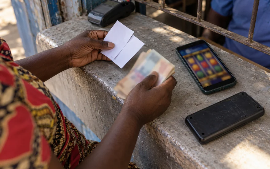 Low deposit casino comparison in Zambia budget comparison illustrated by anonymous betting coupons, blurred banknotes, a slot phone and a blank calculator.